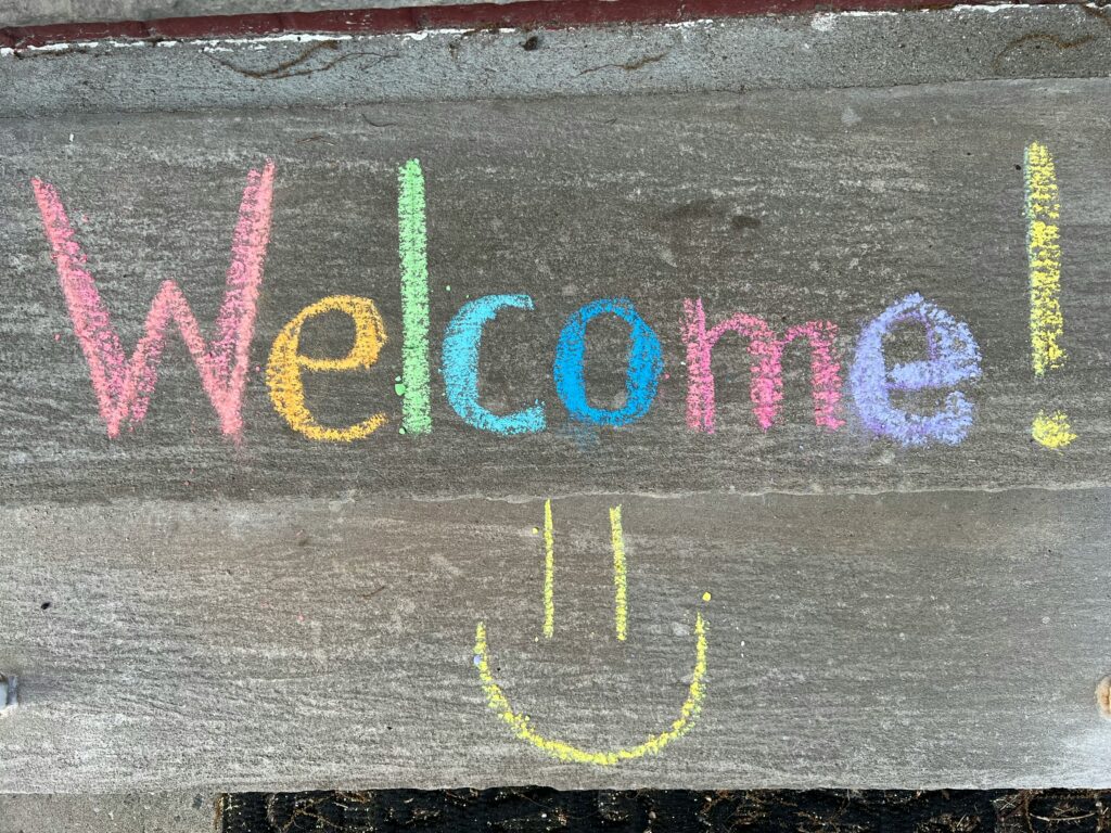 Welcome! written in chalk with a smiley face drawn underneath