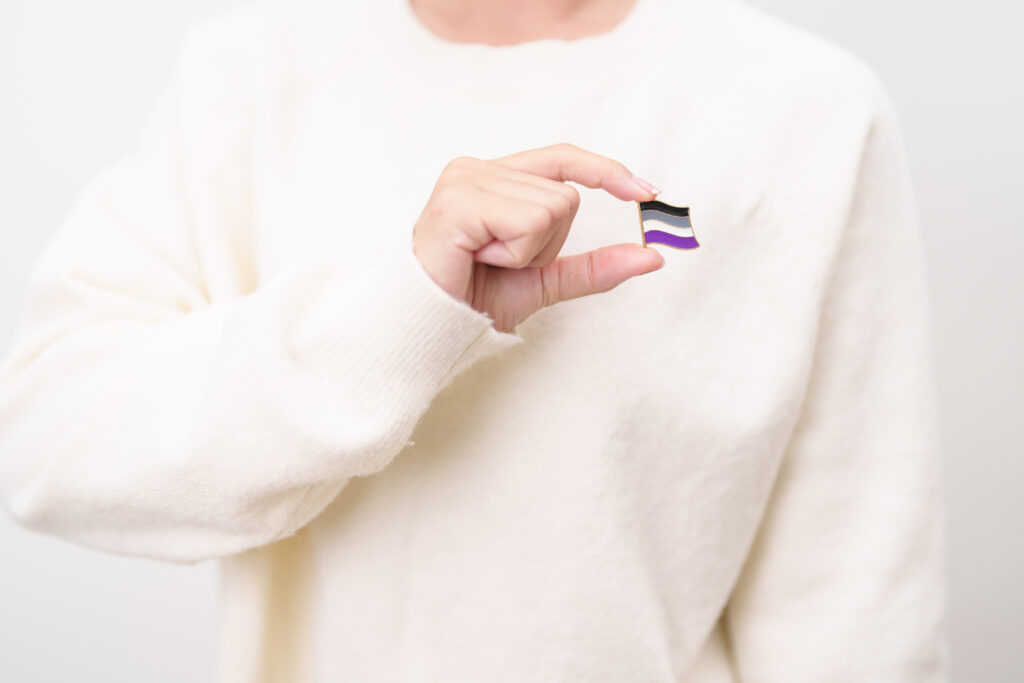 Close-up of a person holding a pin of the asexual flag