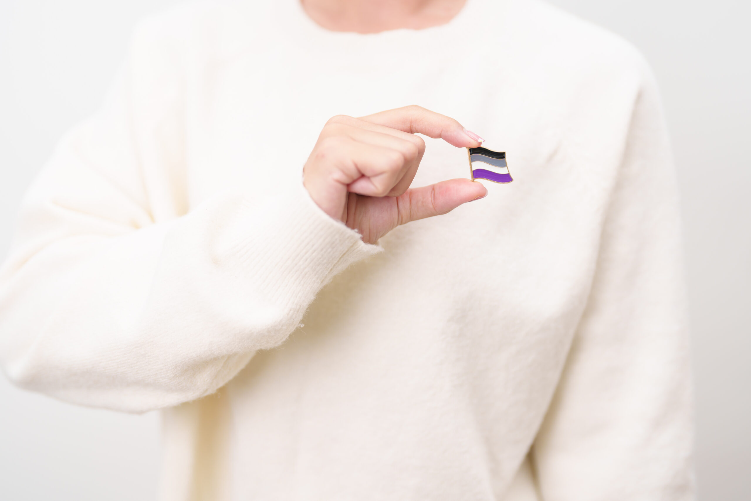 Close-up of a person holding a pin of the asexual flag