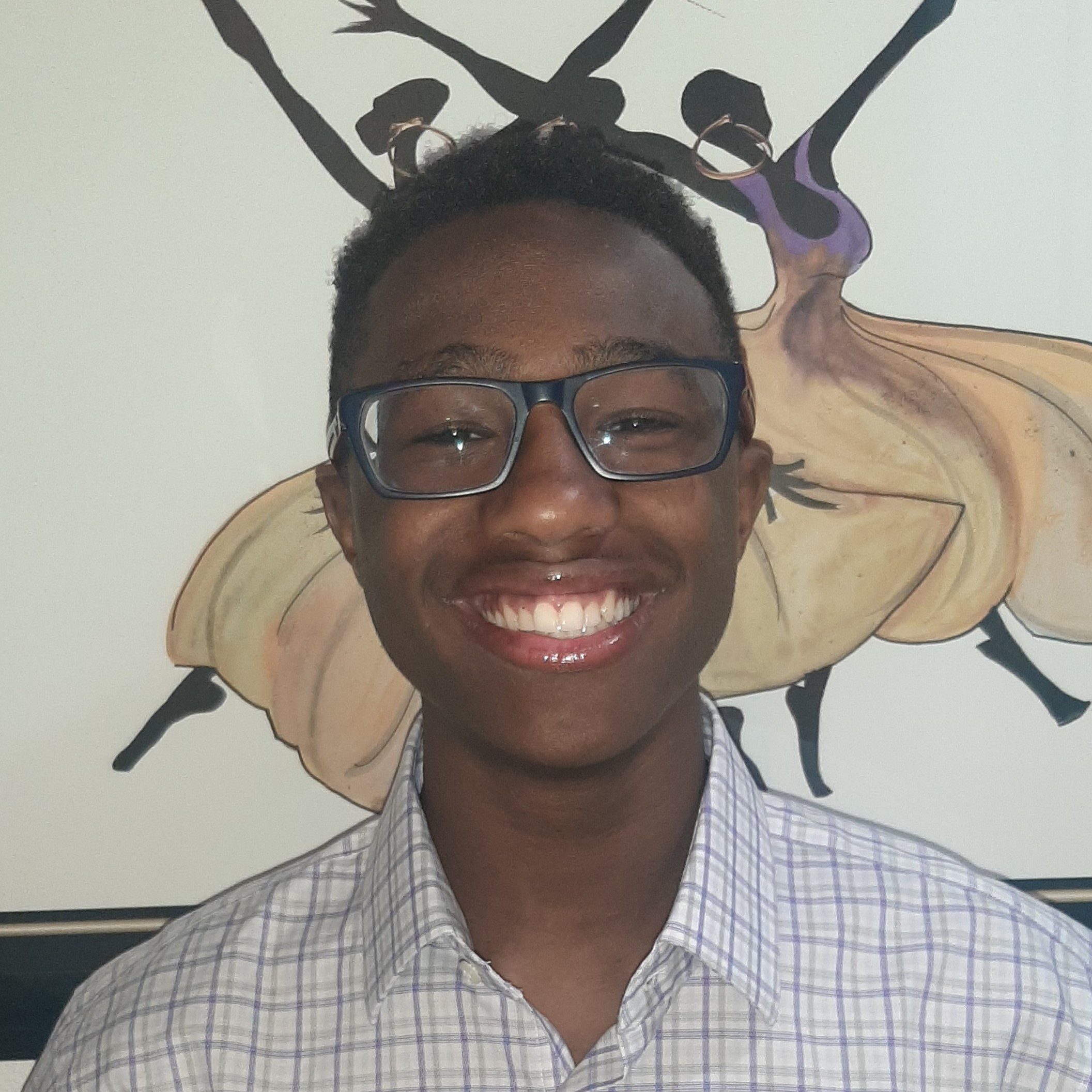 Photo of Jason Scott from the shoulders up, smiling at the camera, wearing white and black checked collared shir tand glasses.