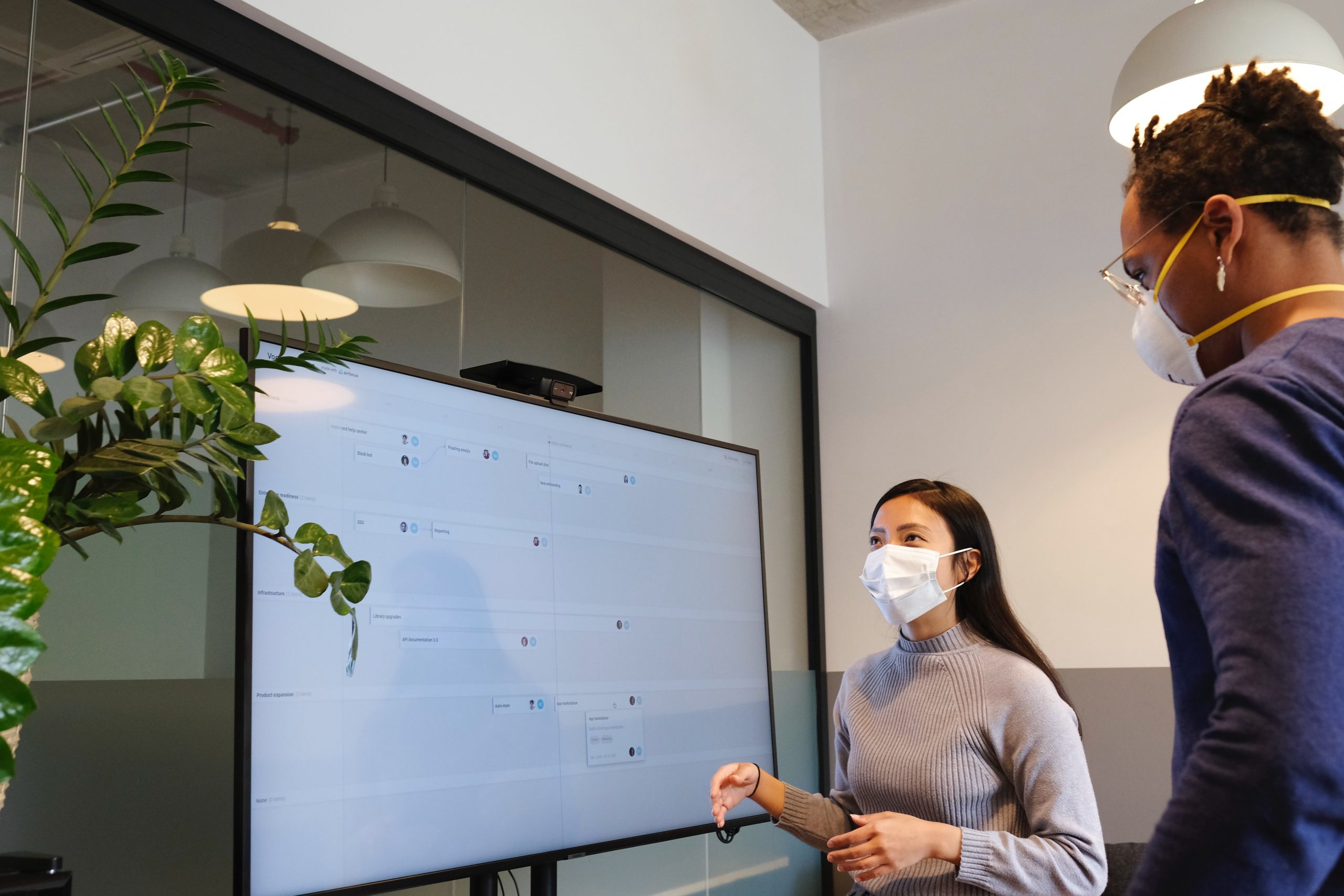 Photograph of two masked adults in front of a white board