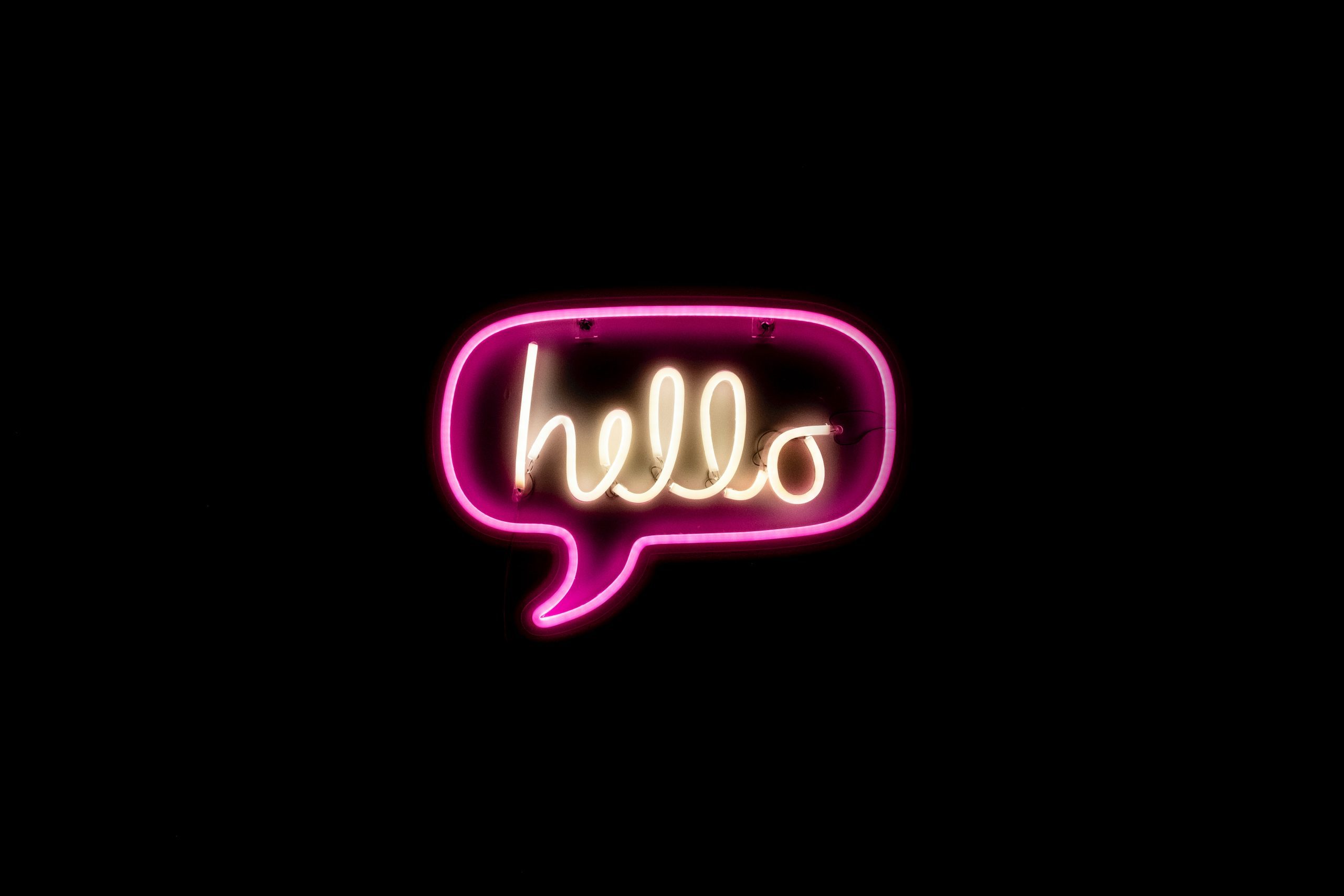 Photo of a neon sign, with a word bubble and the word "hello"
