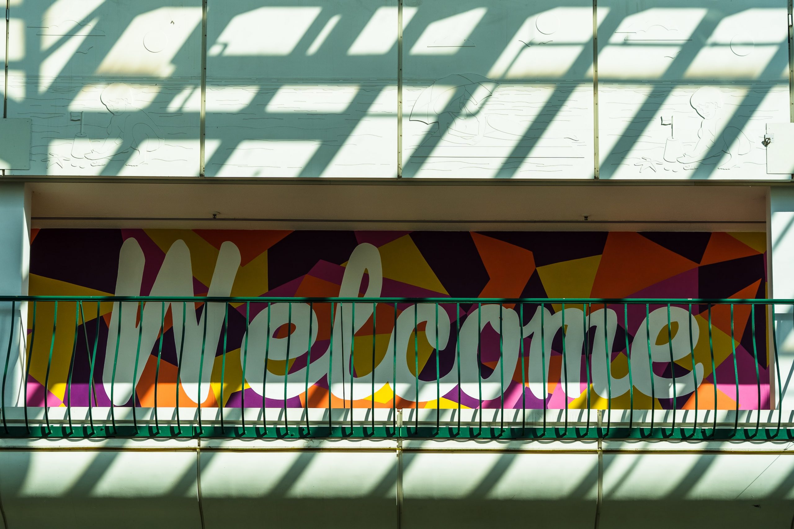 nick-fewings-5zOgGK4biOs-unsplash wooden welcome sign in cursive on a fake shrub background
