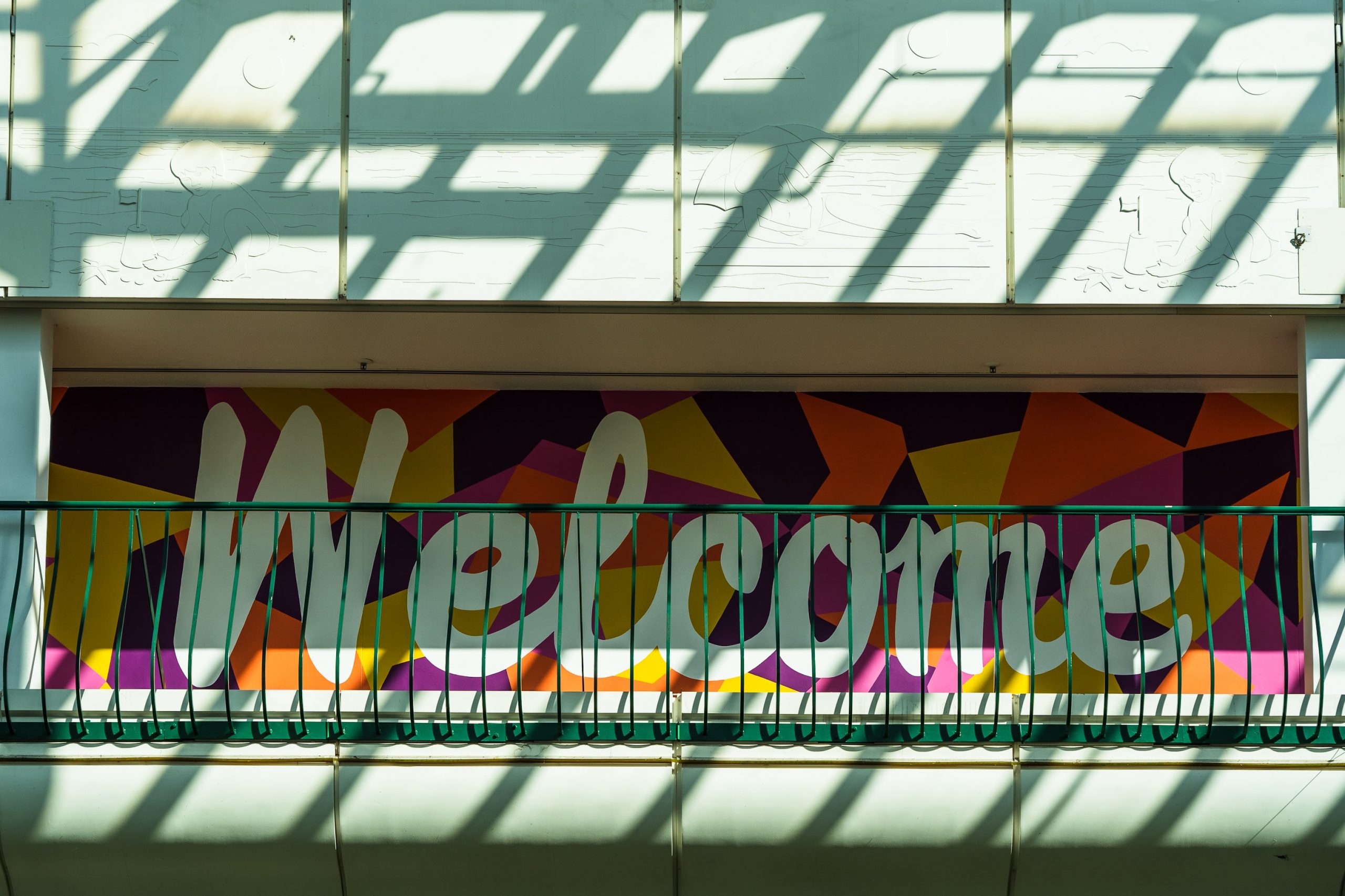 wooden welcome sign in cursive on a fake shrub background