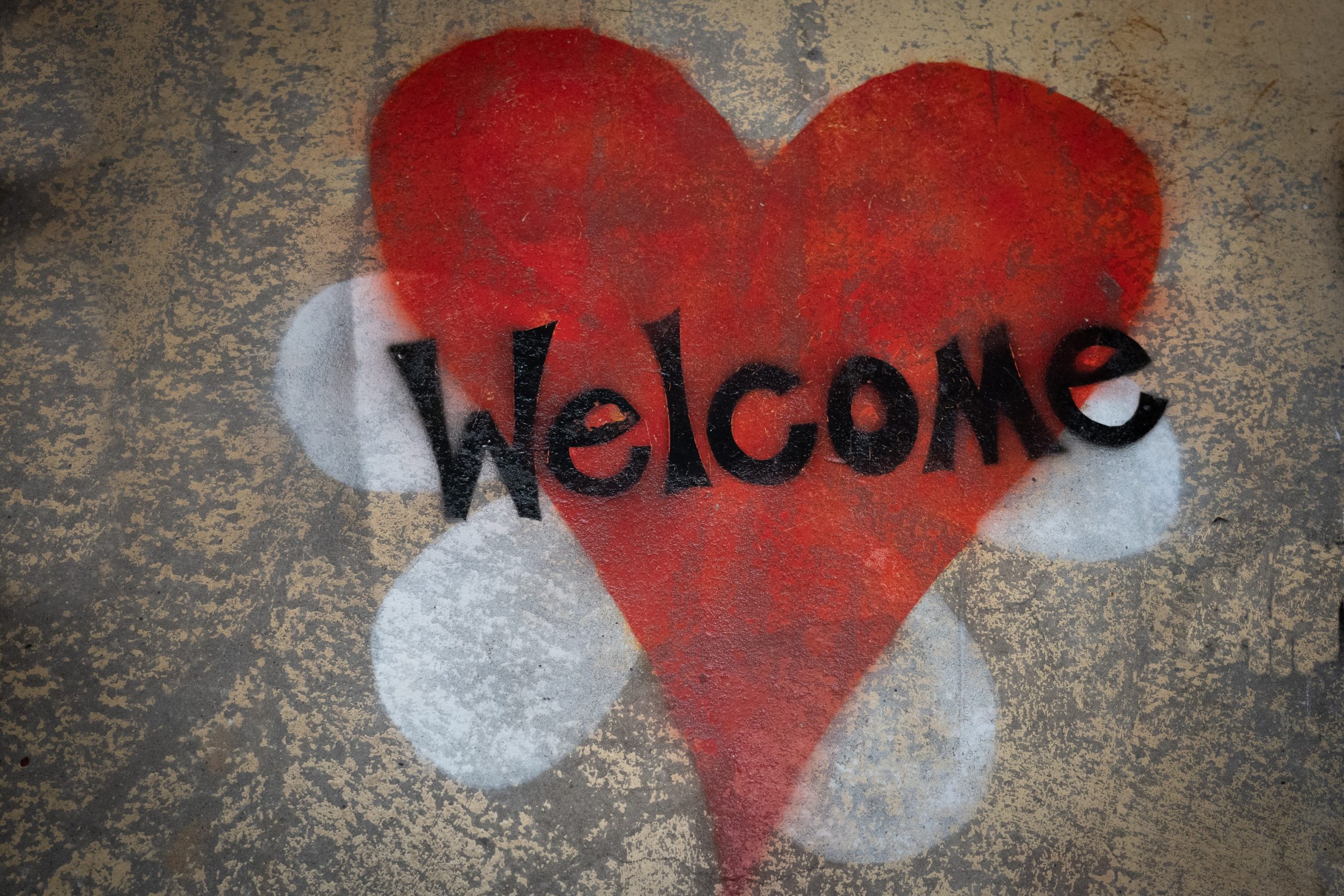 wooden welcome sign in cursive on a fake shrub background